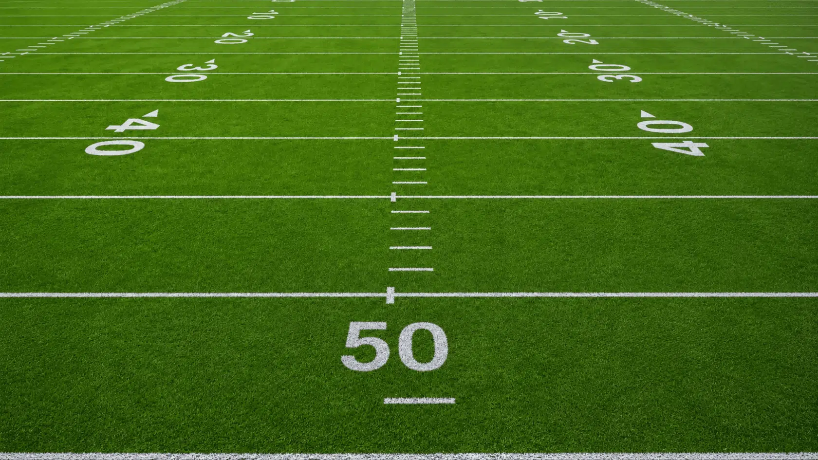 American football field with white yard lines and numbered yard markings on green turf