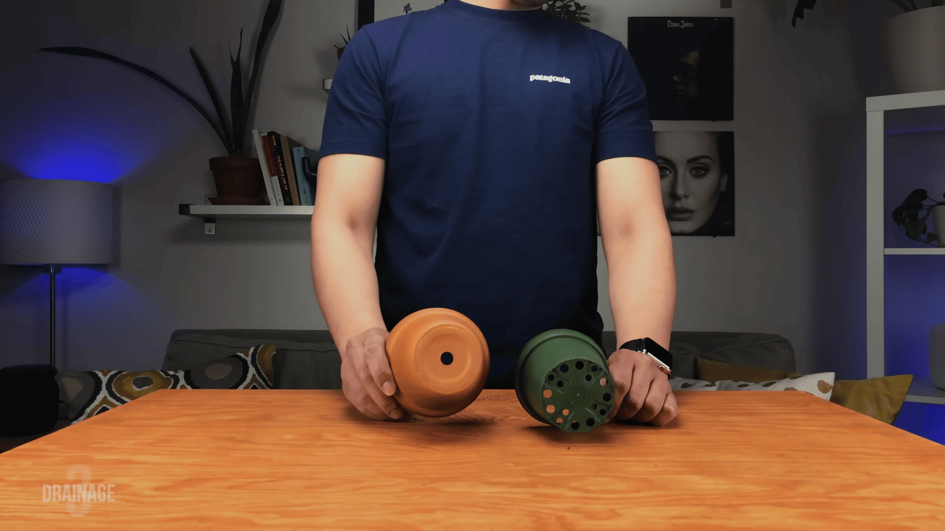 Person showing a terracotta pot with one drainage hole next to a plastic pot with multiple holes.